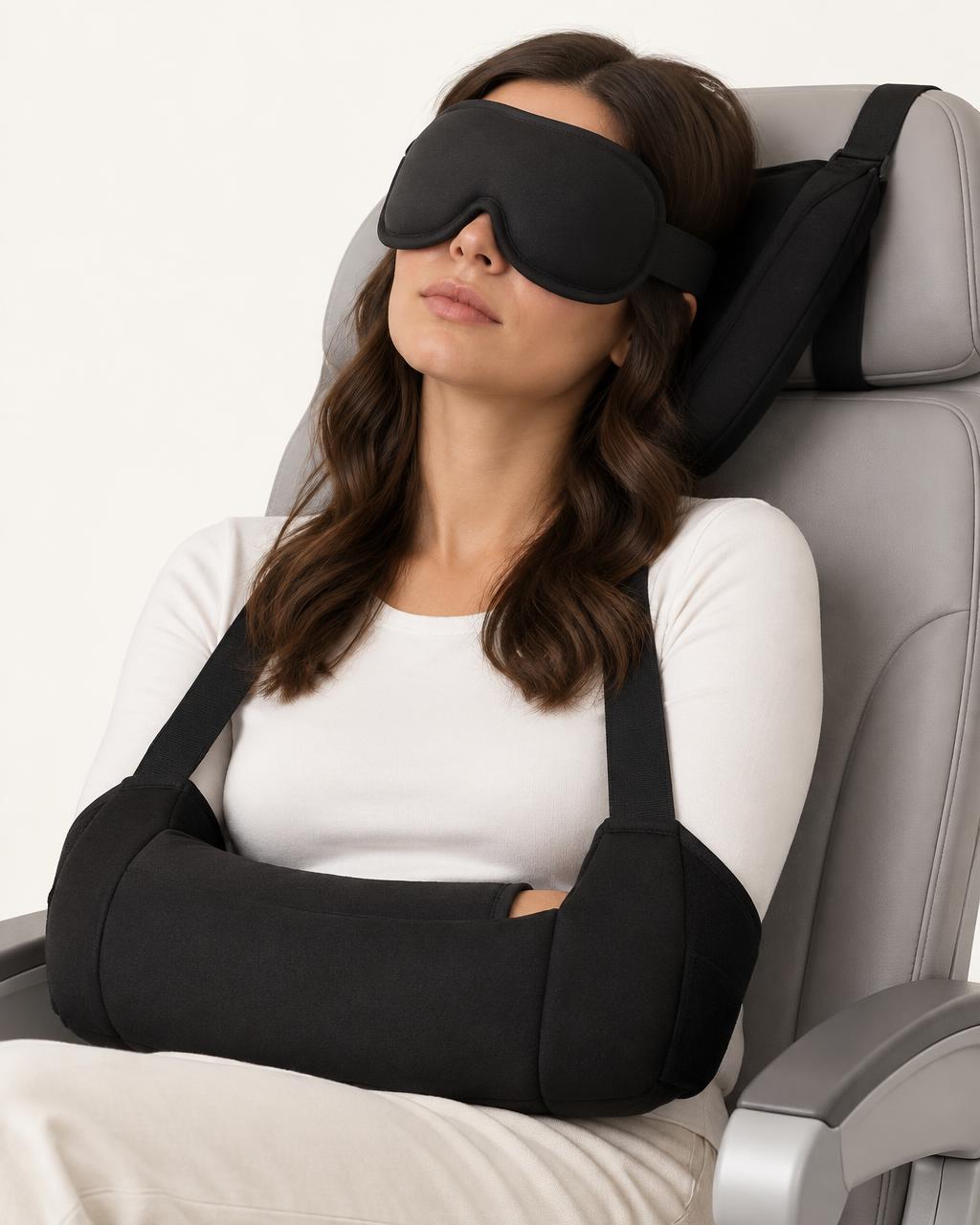 A woman asleep in an airplane seat wearing the black Airwaygirls 3-in-1 travel sleep set: eye mask, head support and arm wrap